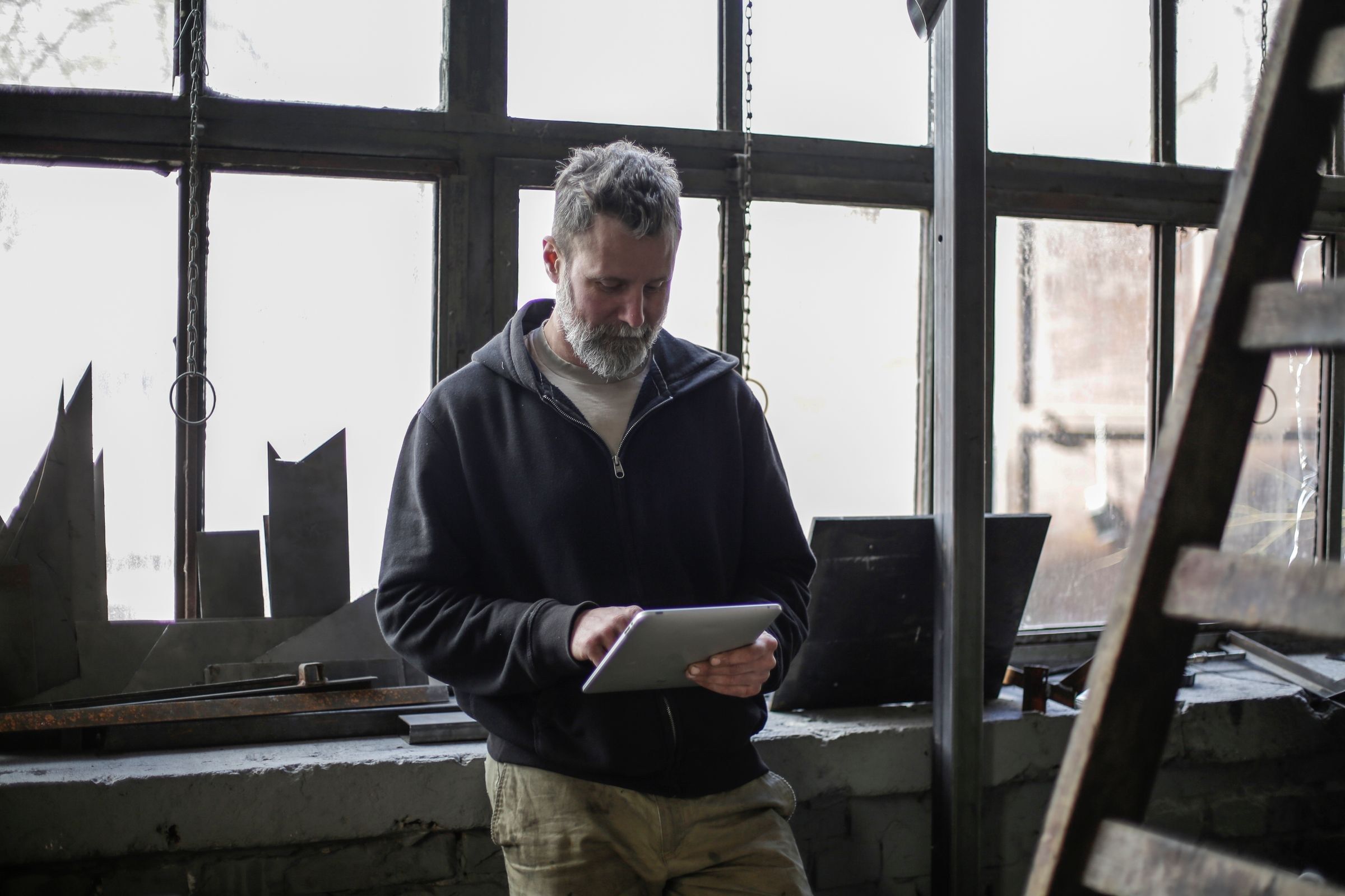 Ein Handwerksmeister prüft in seiner Werkstatt etwas auf dem Tablet.